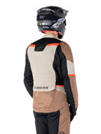 Alpinestars ST-1 Waterproof Jas, Adventure Touring Jas, Dark Khaki Sand Black Red Fluo, achteraanzicht met kleurvlakken van textiel, fluorescerend rode accenten en Alpinestars-logo op de onderrug, gedragen door een rijder met een zwarte helm.