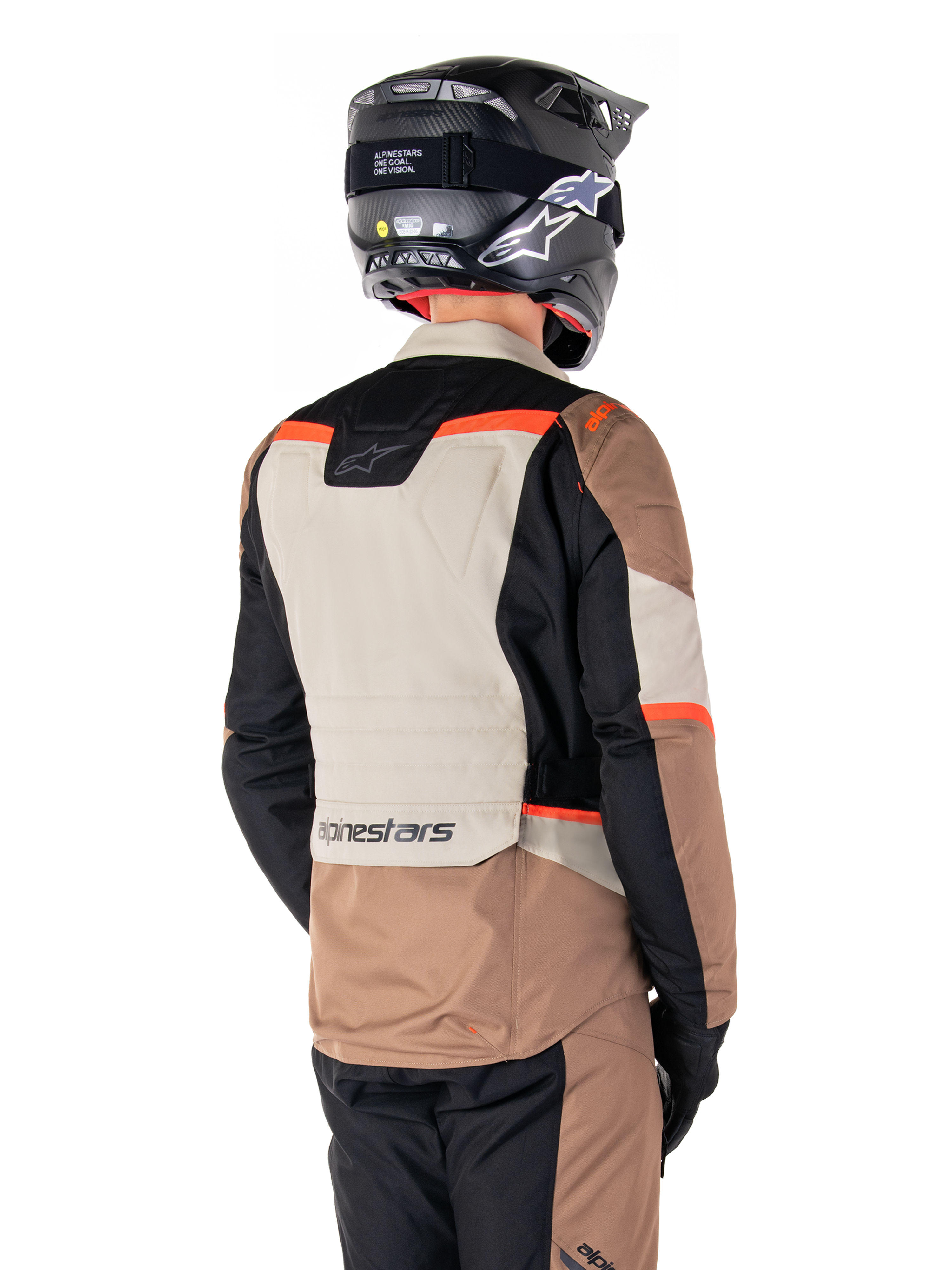 Alpinestars ST-1 Waterproof Jas, Adventure Touring Jas, Dark Khaki Sand Black Red Fluo, achteraanzicht met kleurvlakken van textiel, fluorescerend rode accenten en Alpinestars-logo op de onderrug, gedragen door een rijder met een zwarte helm.