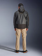 Alpinestars Mospher Waterproof Jacket, zwarte motorparka van achteren gefotografeerd, met MO.ST.EQ-logo op de bovenrug en ripstop-stofconstructie, gedragen met een beige cargobroek en zwarte sneakers, urban commuter-stijl.