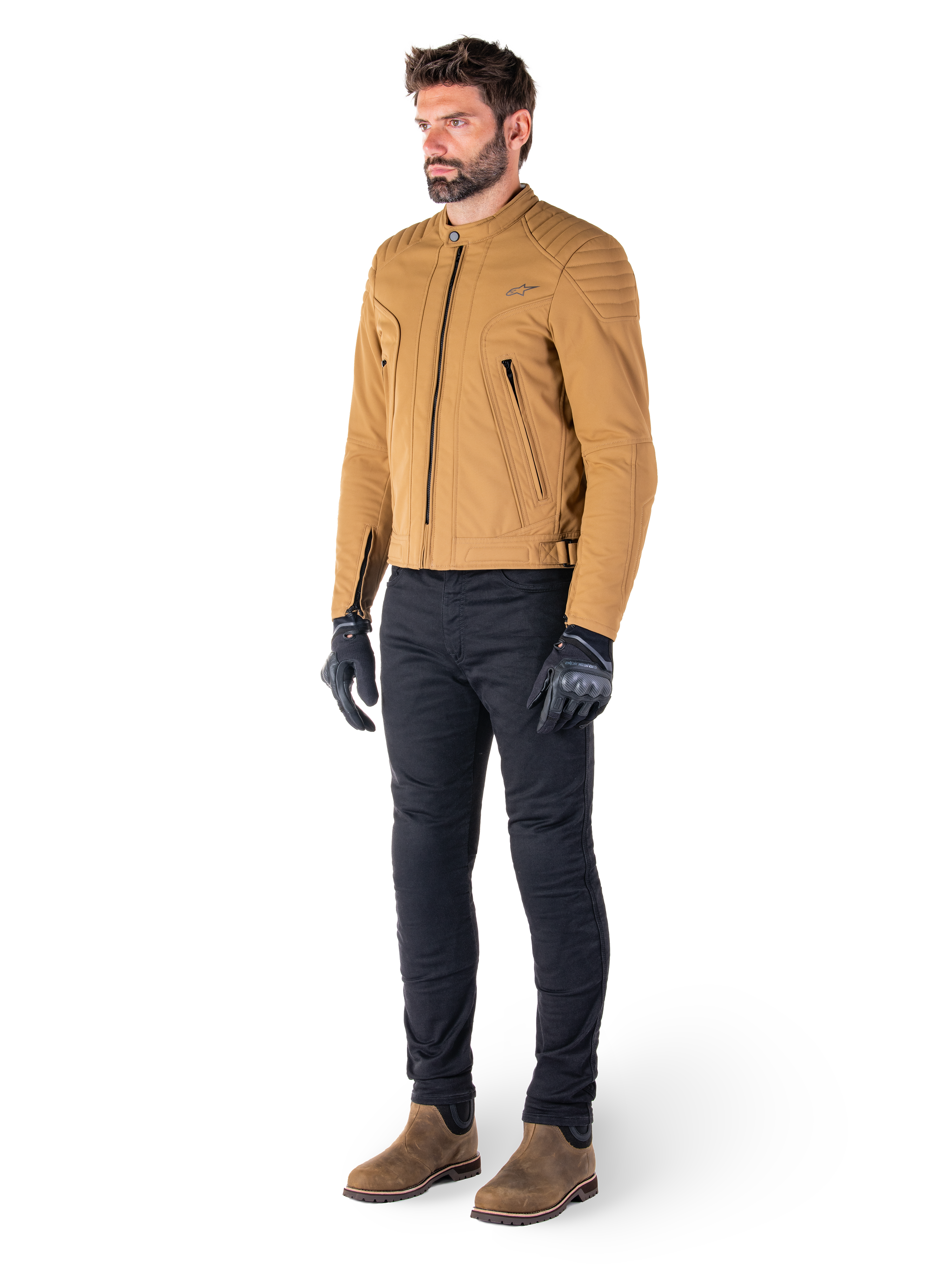 Mannelijke motorrijder draagt de Alpinestars Clayton WR Jas in Utility Brown Light Gold, een urban contemporary motorjas met gewatteerde schouderdetails, gecombineerd met een zwarte broek, zwarte handschoenen en bruine laarzen