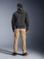 Alpinestars Moblast waterdichte jas, zwart, achteraanzicht van stedelijke motorhoodie, gedragen met beige cargo broek en zwarte sneakers, minimalistisch ontwerp met verticale 'astars' branding op de bovenrug, eigentijdse motorkleding voor alle weersomstandigheden