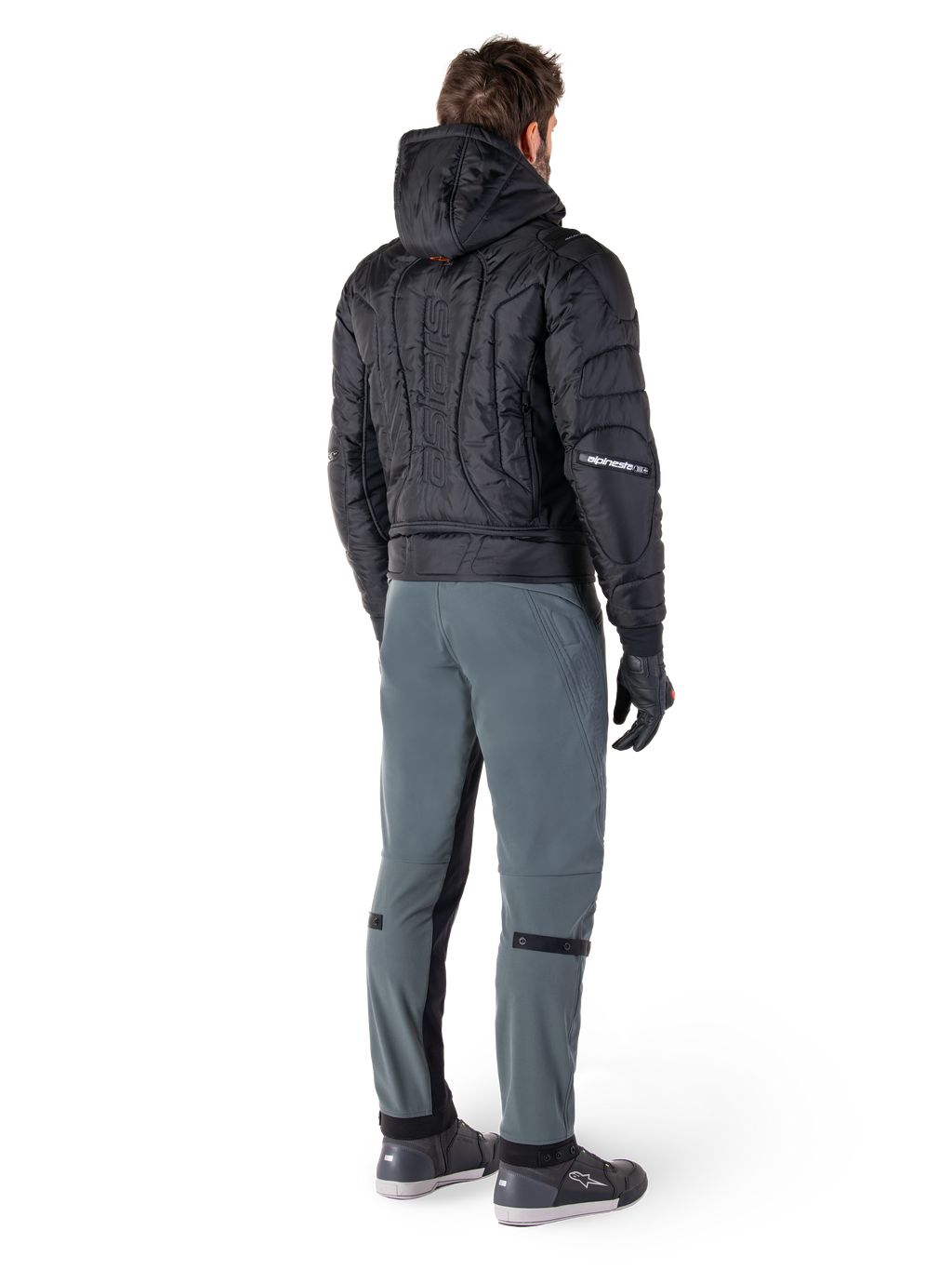 Alpinestars Mohobbs Waterproof Jacket, zwart, achteraanzicht van gewatteerd bomberjack met verticaal woordmerk in reliëf op de rug, gestyled met grijze motorbroek en zwarte handschoenen, op urban streetwear geïnspireerde motorkleding