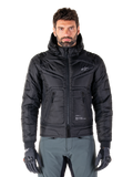 Alpinestars Mohobbs Waterproof Jacket, zwarte gewatteerde bomber motorjas, gewatteerde poly-stof met ritssluiting en ritszakken, klein wit logo op de borst, gedragen door een model met grijze broek en handschoenen, urban streetwear-ontwerp voor rijden in de stad