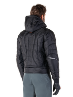 Alpinestars Mohobbs Waterproof jas, zwart, achteraanzicht met gewatteerde constructie, capuchon, verticaal astars-woordmerk op de rug en Alpinestars-branding op de mouwen, gedragen met grijze broek en zwarte handschoenen.