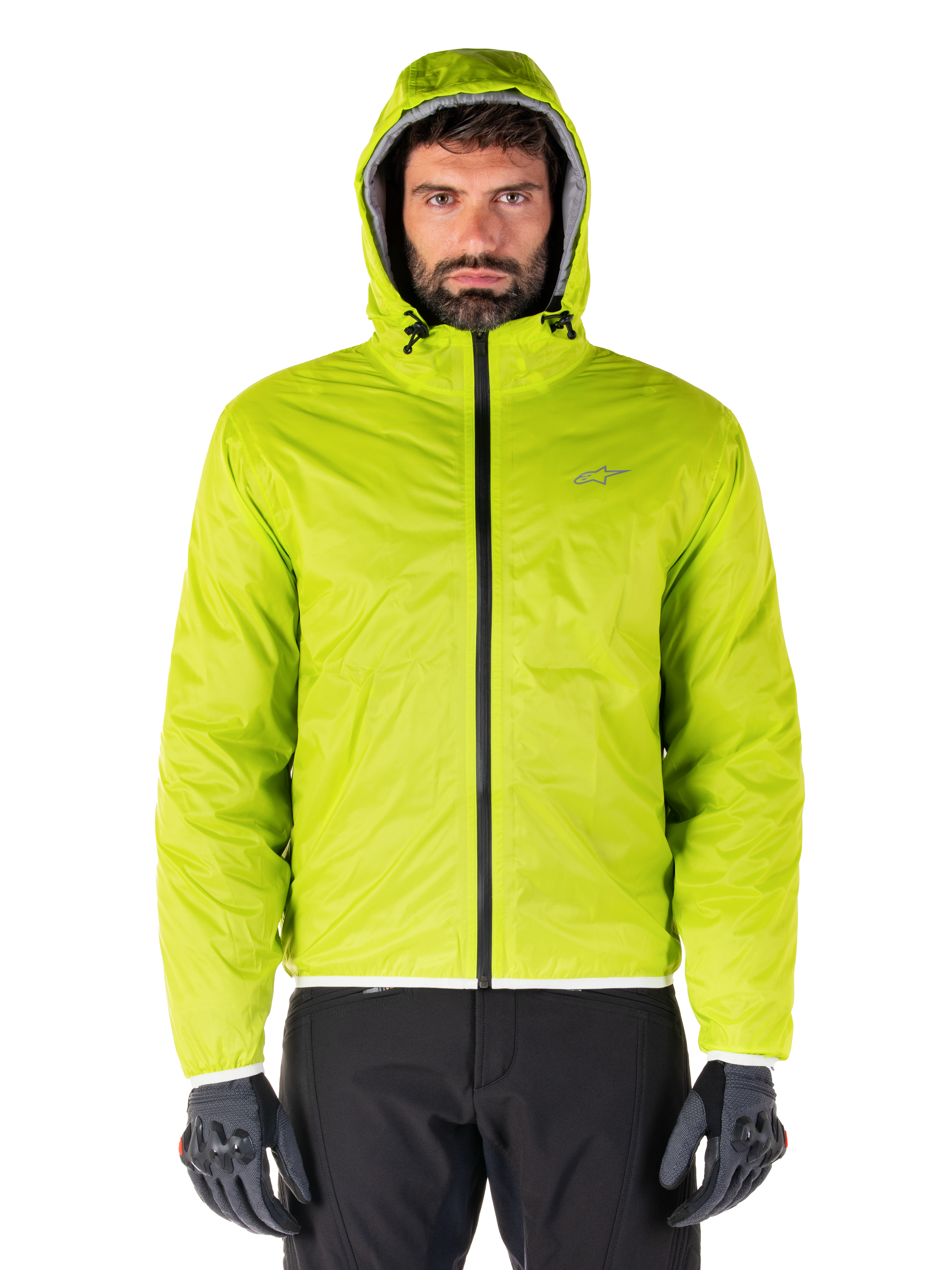 Alpinestars Mohobbs Waterproof Jacket, Lime Punch opvouwbare regenhoes, fel limoengroene shell met capuchon gedragen met zwarte motorbroek en grijze motorhandschoenen, urban moto-streetwear stijl.