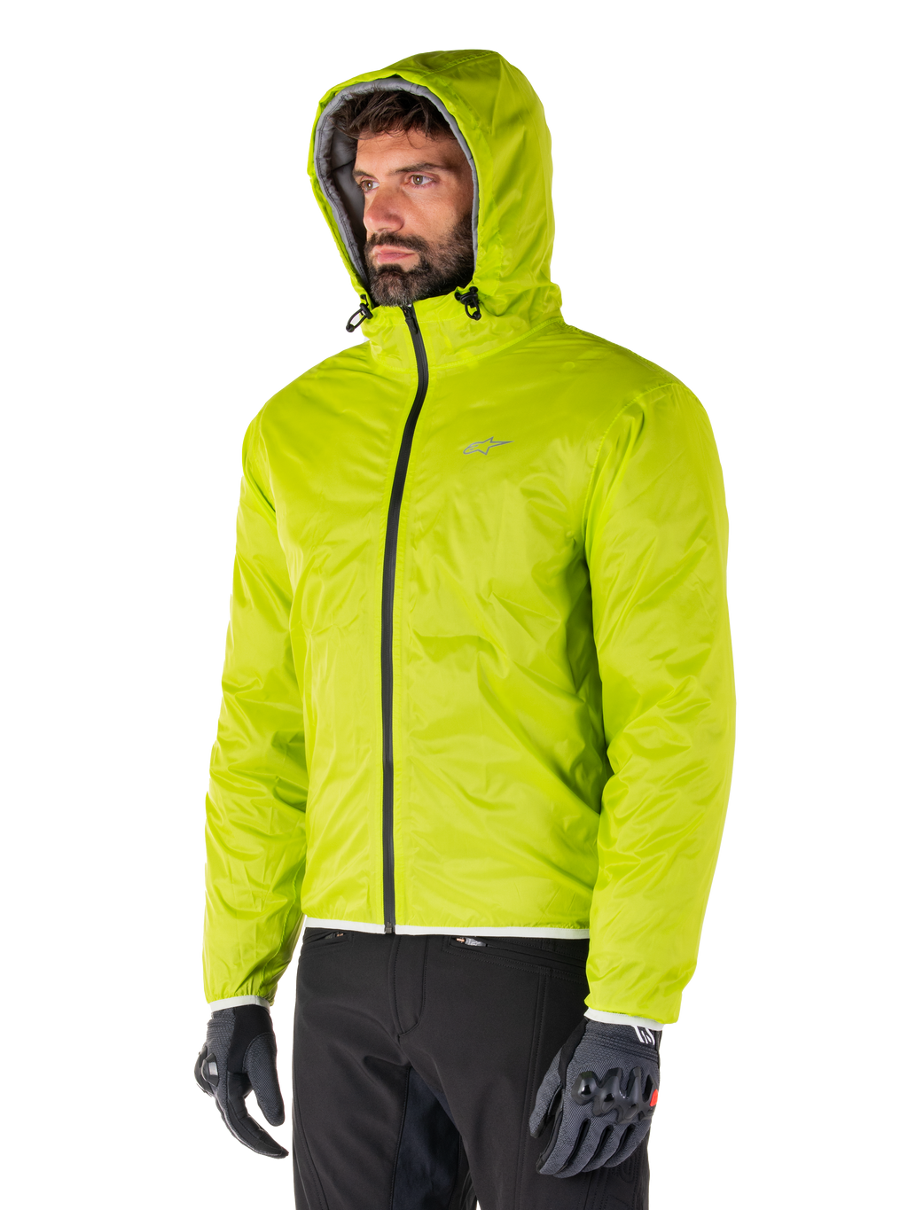 Alpinestars Mohobbs Waterproof Jacket, Lime Punch opvouwbare regenvoering, fel neongroene jas met capuchon gedragen met zwarte broek en grijze handschoenen, op urban streetwear geïnspireerde motorkleding