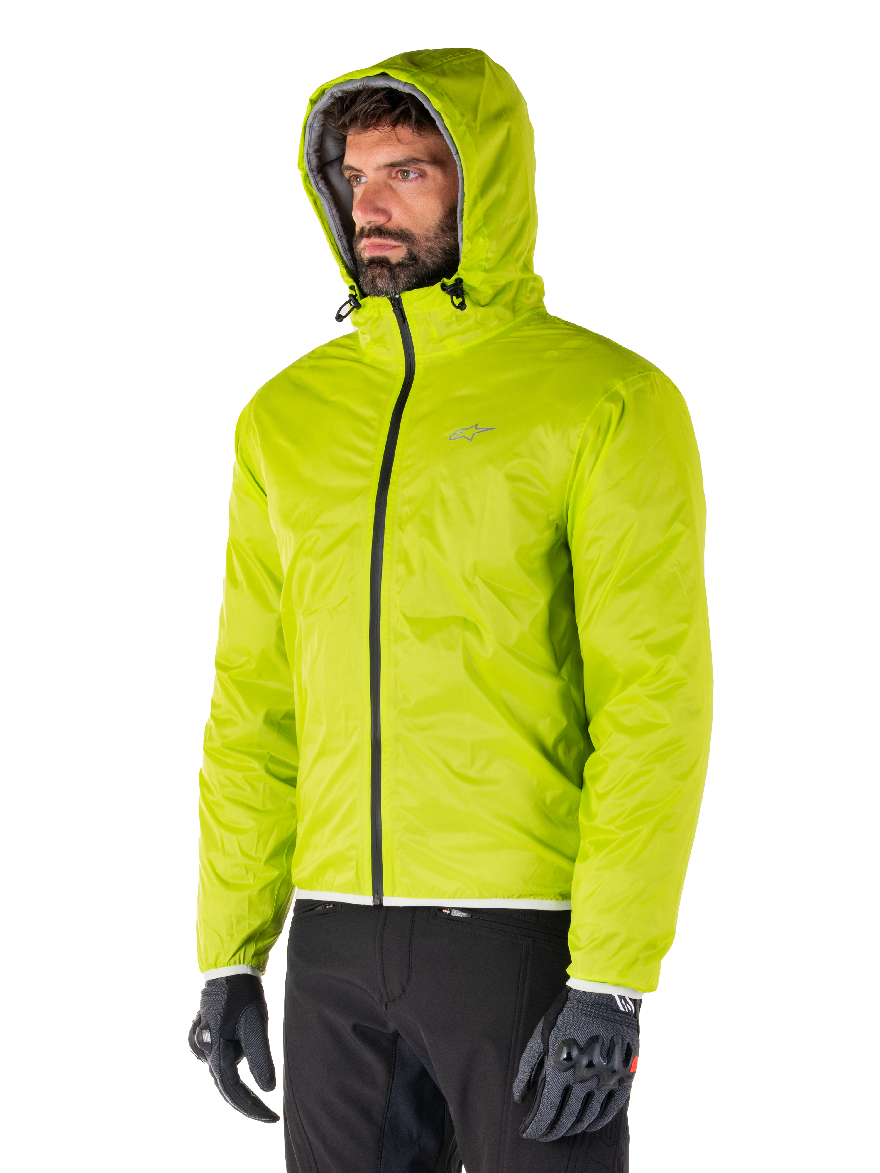 Alpinestars Mohobbs Waterproof Jacket, Lime Punch opvouwbare regenvoering, fel neongroene jas met capuchon gedragen met zwarte broek en grijze handschoenen, op urban streetwear geïnspireerde motorkleding