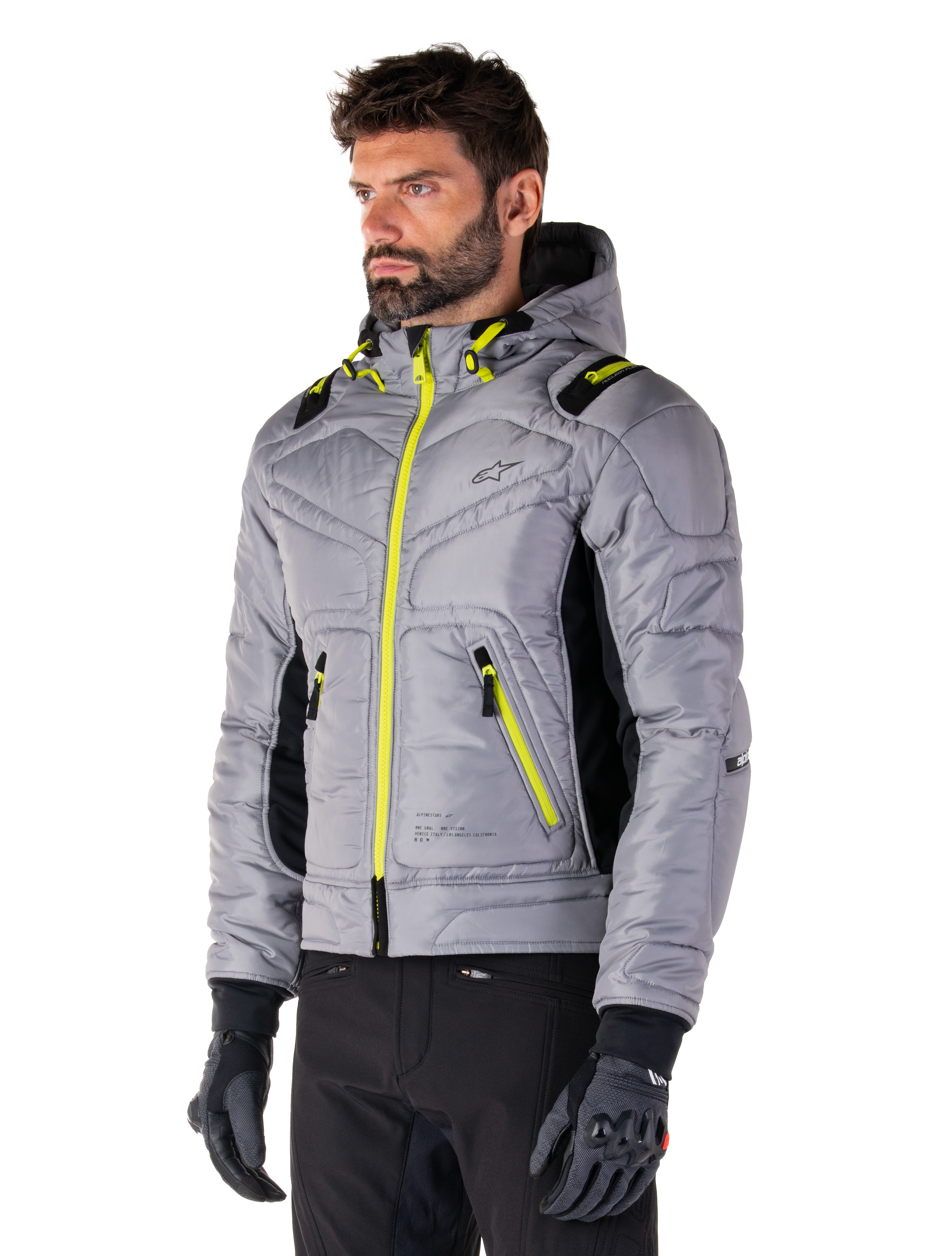 Alpinestars Mohobbs Waterproof Jacket, Lunar Gray Lime Punch, gewatteerd bomberjack voor heren met neongele ritsen en trekkoordaccenten, gedragen met zwarte motorbroek en handschoenen, modern urban moto streetwear-ontwerp met een capuchon