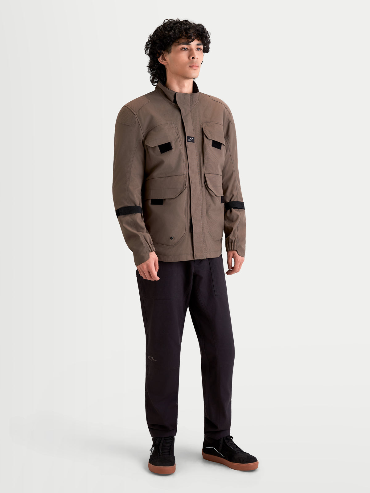 Alpinestars Altan Drystar Jas, heren urban contemporary textiel motorjas in walnootbruin en zwart, vooraanzicht op model die het waterdichte field-jacket model met utility-cargozakken draagt