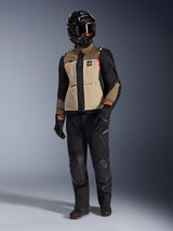 Alpinestars Andes Pro Drystar® XF Jacket in Walnut Aluminum, adventure motorcycle jacket worn with matching black pants, a black adventure helmet with goggles, and black boots, featuring tan and black panels with red accents.