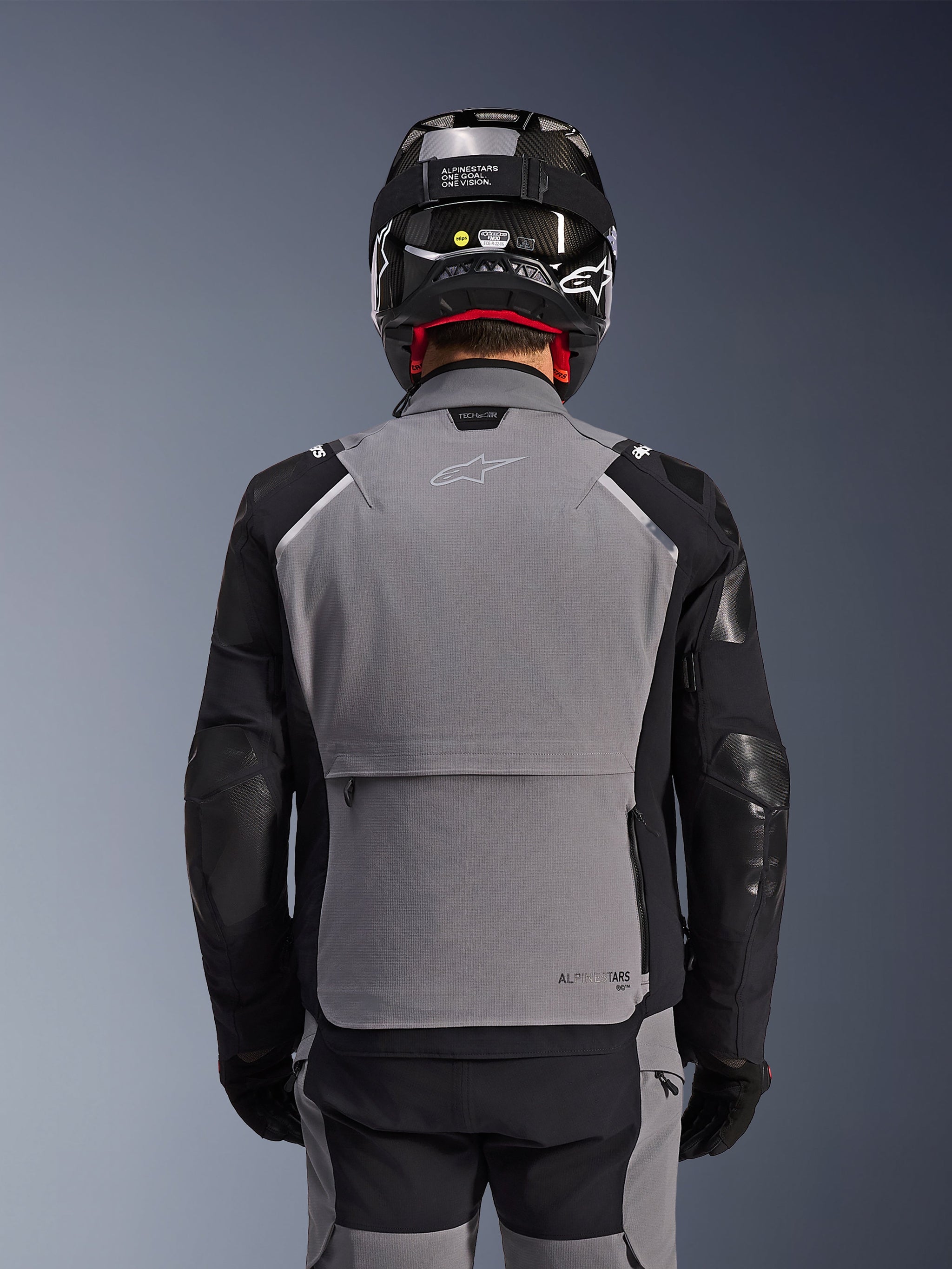 Alpinestars Andes Pro Drystar® XF Jacket, Dark Gray and Black, back view showing large rear storage pocket and Tech-Air branding, worn by a rider with a black helmet and matching riding pants, professional adventure touring gear
