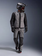 Adventure-rijder in Alpinestars Andes Pro Drystar® XF Jas in donkergrijs en zwart, bijpassende adventure-broek, zwarte Alpinestars-helm met bril, zwarte handschoenen en laarzen, complete technische touring-uitrusting voor lange afstanden