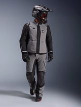 Adventure rider wearing Alpinestars Andes Pro Drystar® XF Jacket in Dark Gray and Black, matching adventure pants, black Alpinestars helmet with goggles, black gloves and boots, complete technical touring gear for long-distance riding