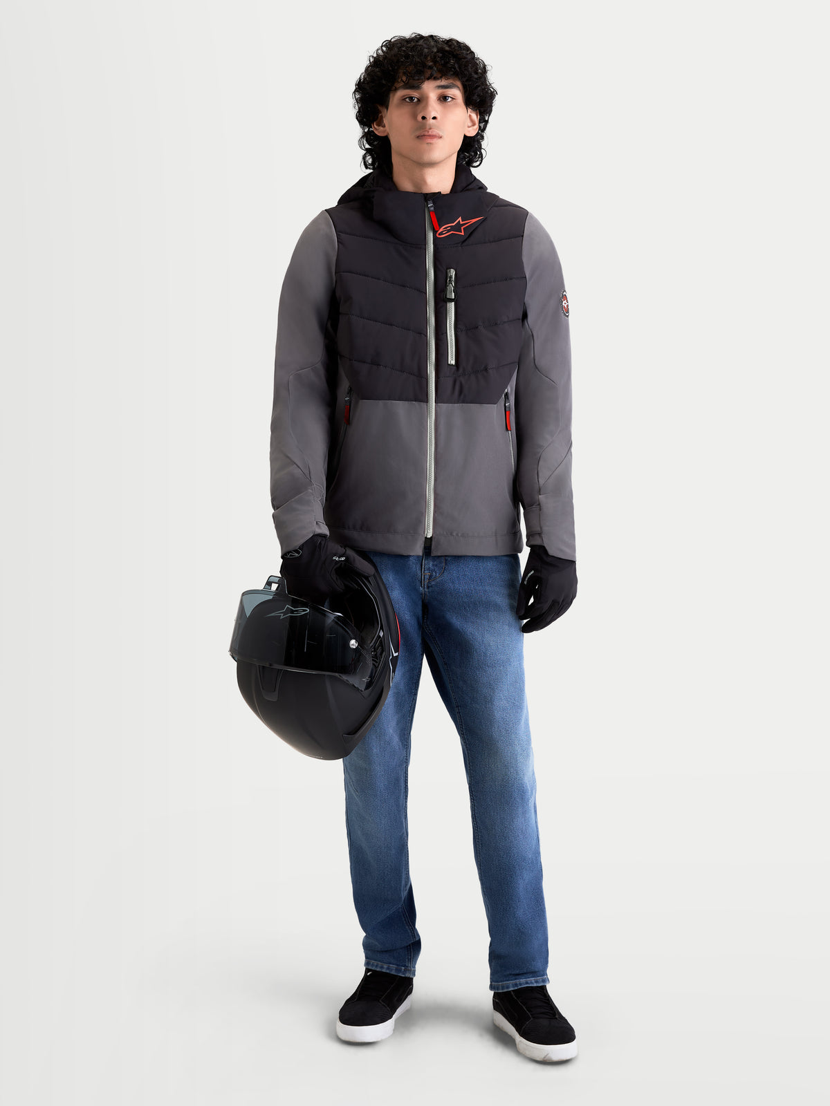 Alpinestars Therma-Tech Waterdichte Jas, heren motorjas voor stedelijk gebruik in zwart en donkergrijs, vooraanzicht op model met spijkerbroek, handschoenen en helm