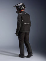 Alpinestars Cusco Drystar® Jacket in Black, rear-side view of a rider wearing a full adventure touring kit including matching black pants and gloves, black adventure helmet, textile construction with reflective branding on the back