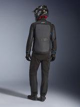Alpinestars Cusco Drystar® Jacket, zwart en donkergrijs, achteraanzicht van een motorrijder die volledige adventure touring-uitrusting draagt, groot grijs rugpaneel met Alpinestars-logo, blauwe accenten op de mouwen, gedragen met bijpassende zwarte broek en helm.