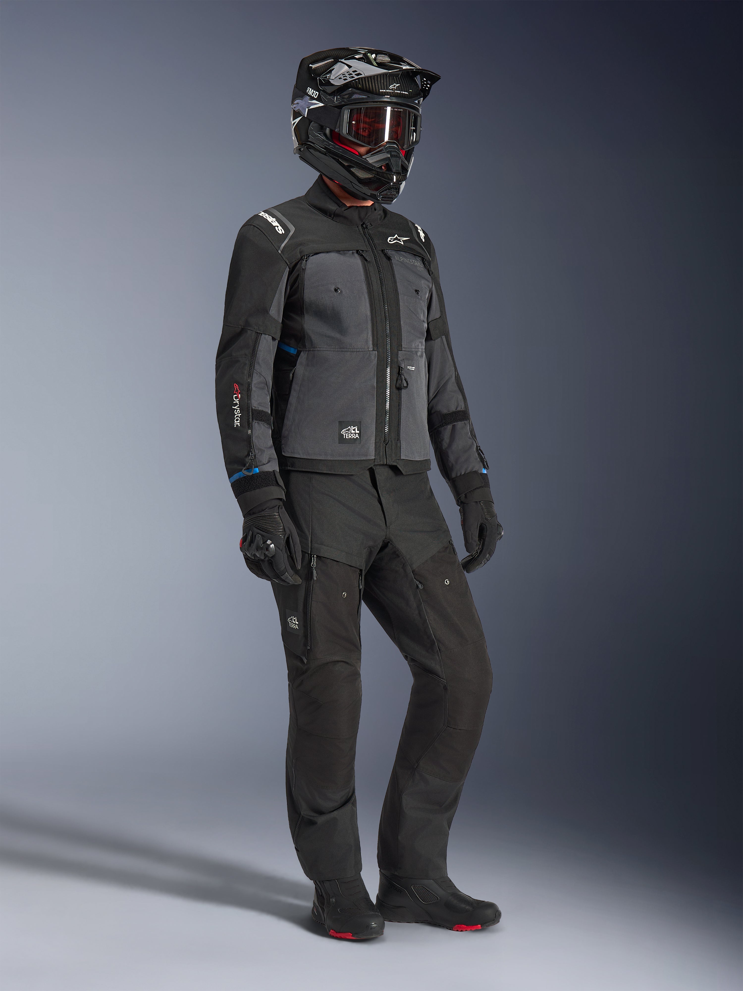 Model wearing Alpinestars Cusco Drystar® Jacket in Black and Deep Gray, paired with full motorcycle riding gear including a black helmet, matching technical pants, gloves, and boots, featuring ripstop and softshell construction for road and adventure touring