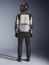 Motorrijder van achteren gezien met de Alpinestars Cusco Drystar® Jas in Ice Gray, Mid Gray en Deep Gray, voorzien van een groot ventilatiepaneel op de rug en Alpinestars-branding, gecombineerd met een zwarte motorbroek en een zwarte helm, adventure touring motorkleding