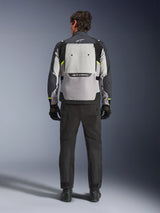 Achteraanzicht van een motorrijder die de Alpinestars Cusco Drystar® Jas draagt in Ice Gray, Mid Gray en Deep Gray, gecombineerd met een zwarte motorbroek en handschoenen, met de nadruk op het grote ventilatiepaneel aan de achterzijde en Alpinestars-branding