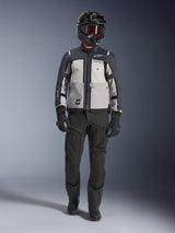 Alpinestars Cusco Drystar® Jas, Ice Gray Mid Gray Deep Gray, adventure motorjas gedragen met een zwarte motorbroek, zwarte handschoenen en een zwarte helm met motorbril, voorzien van grijze kleurvlakken en technische details voor road- en adventure-touring.
