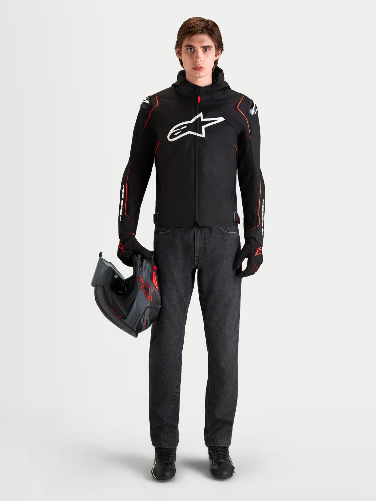Alpinestars Zaca V 2 Waterproof Jas, heren motorjas voor sportief rijden, zwart en rood, met DFS-schouderbescherming en geïntegreerde capuchon, gedragen door een model dat een helm vasthoudt