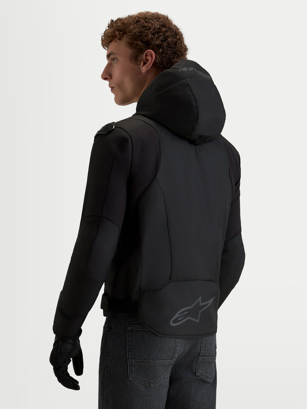 Alpinestars Zaca V2 Waterproof jas, heren-motorjas in zwart met geïntegreerde capuchon, verlengde achterzoom met Alpinestars-logo en Tech-Air-ready constructie, achteraanzicht.