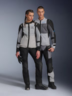 Mannelijke en vrouwelijke modellen die Alpinestars ST-2 Air-jassen dragen in Ice Gray, Dark Gray en Black, technische zomer-touringmotorkleding met grote mesh-panelen en 'exploration equipment'-branding, gecombineerd met zwarte motorbroeken, handschoenen en laarzen.