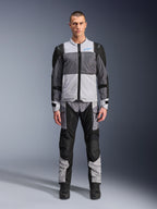 Alpinestars ST-2 Air Jas, motor-toerjas, Ice Gray, donkergrijs en zwart, gedragen door een model met bijpassende adventure-broek, voorzien van grote mesh-panelen, blauw Alpinestars-logo op de borst en Alpinestars Exploration Equipment-branding.