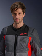 Alpinestars ST-2 Air jas, Deep Gray, Dark Gray en Bright Red, zomer touring motorjas gedragen door een model, voorzien van mesh ventilatiepanelen, rood Astars-logo en 'Exploration Equipment' branding op de borst