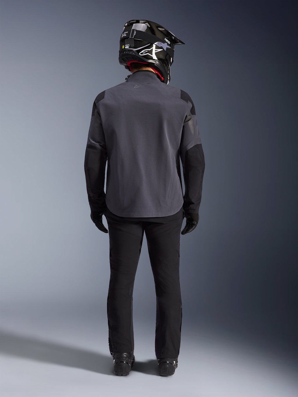 Alpinestars Maxdura Drystar®XF Laminated Armored Shell, Deep Gray Black, volledig achteraanzicht, technische adventure motorjas met verstevigde panelen, gedragen met zwarte motorbroek, handschoenen en een zwart-witte off-road helm, gecoördineerd dual-sport kledingensemble