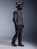 Motorrijder in Alpinestars Maxdura Drystar®XF Laminated Armored Shell jas in Deep Gray en Black, zwarte adventure motorbroek, zwarte helm met motorbril, zwarte handschoenen en laarzen, volledige studio-opname van de technische dual-sport uitrusting