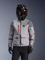 Alpinestars Maxdura Drystar®XF Laminated Armored Shell, adventure motorcycle jacket in Mid Gray and Dark Gray, worn with a black carbon-finish helmet and red-tinted goggles, featuring front cargo pockets and a red chest zipper, technical design for adventure touring.