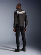 Mannelijk model van achteren gezien die de Alpinestars T-Dyno WR Jas in Black Dark Gray Ecru draagt, textiele motorjas met een horizontale streep en sterlogo op de rug, gecombineerd met een zwarte motorbroek en laarzen, urban motoruitrusting esthetiek.