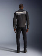 Alpinestars T-Dyno WR Jas, textiele motorjas, zwart, donkergrijs en ecru, achteraanzicht met horizontale streep over de schouders en klein sterlogo, gedragen door model met zwarte broek en laarzen, vintage-geïnspireerde motorkleding