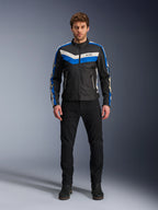 Alpinestars T-Dyno WR Jacket, textiele motorjas, zwart, blauw en ecru, gedragen door een mannelijk model met zwarte broek en laarzen, met chevron-strepen op de borst en erfgoed biker-ontwerp
