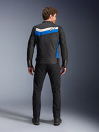 Alpinestars T-Dyno WR Jas, textiele motorjas, kleurstelling Black Blue Ecru, volledig achteraanzicht op model, voorzien van een blauwe en ecru chevron-streep met Alpinestars-logo, gecombineerd met zwarte broek en laarzen, vintage-geïnspireerde urban motorkleding