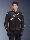 Alpinestars T-GP R V3 Drystar motorjas, waterdichte sportieve textieljas, zwart en wit met rode accenten, voorzien van een groot wit sterlogo op de borst en witte merknaam op de mouwen, gedragen met zwarte en rode motorhandschoenen
