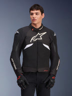 Alpinestars T-GP R V3 Drystar motorjas, waterdichte sportieve textieljas, zwart en wit met rode accenten, voorzien van een groot wit sterlogo op de borst en witte merknaam op de mouwen, gedragen met zwarte en rode motorhandschoenen