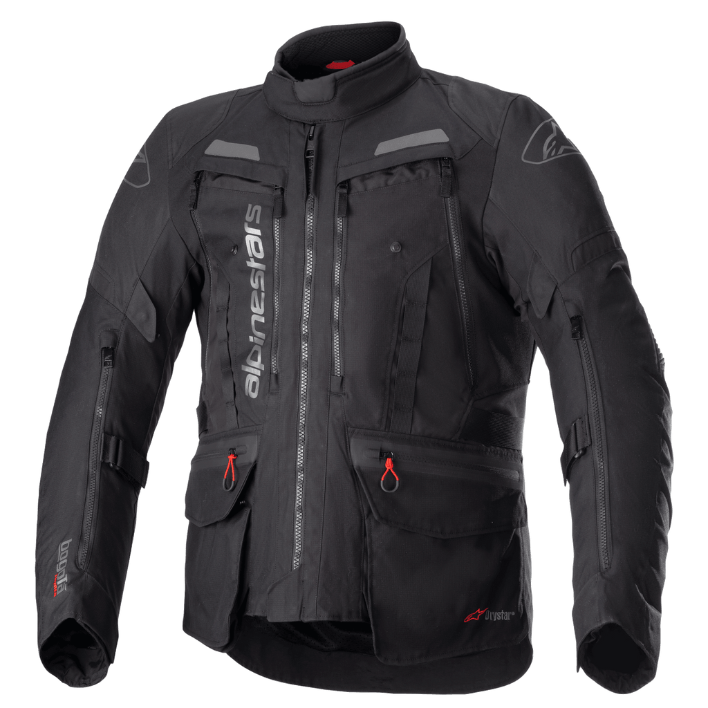 Alpinestars Bogota Pro Drystar motorjas, volledig zwarte motorjas voor touring, grijze en rode accenten, voorzien van grote ventilatiepanelen op de borst, waterdichte zakken met rode treklipjes, hoge beschermende kraag en duurzame textielconstructie voor adventure rijden