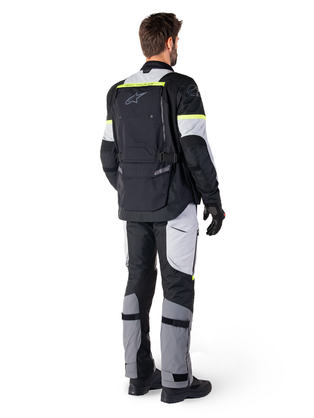 Achteraanzicht van een motorrijder die de Alpinestars Bogotá Pro Drystar® Jas in Black Ice Gray Yellow Fluo draagt, gecombineerd met bijpassende adventure touring broek, voorzien van een grote achterzak en fluorescerend gele accenten, all-season textiele motorkleding.