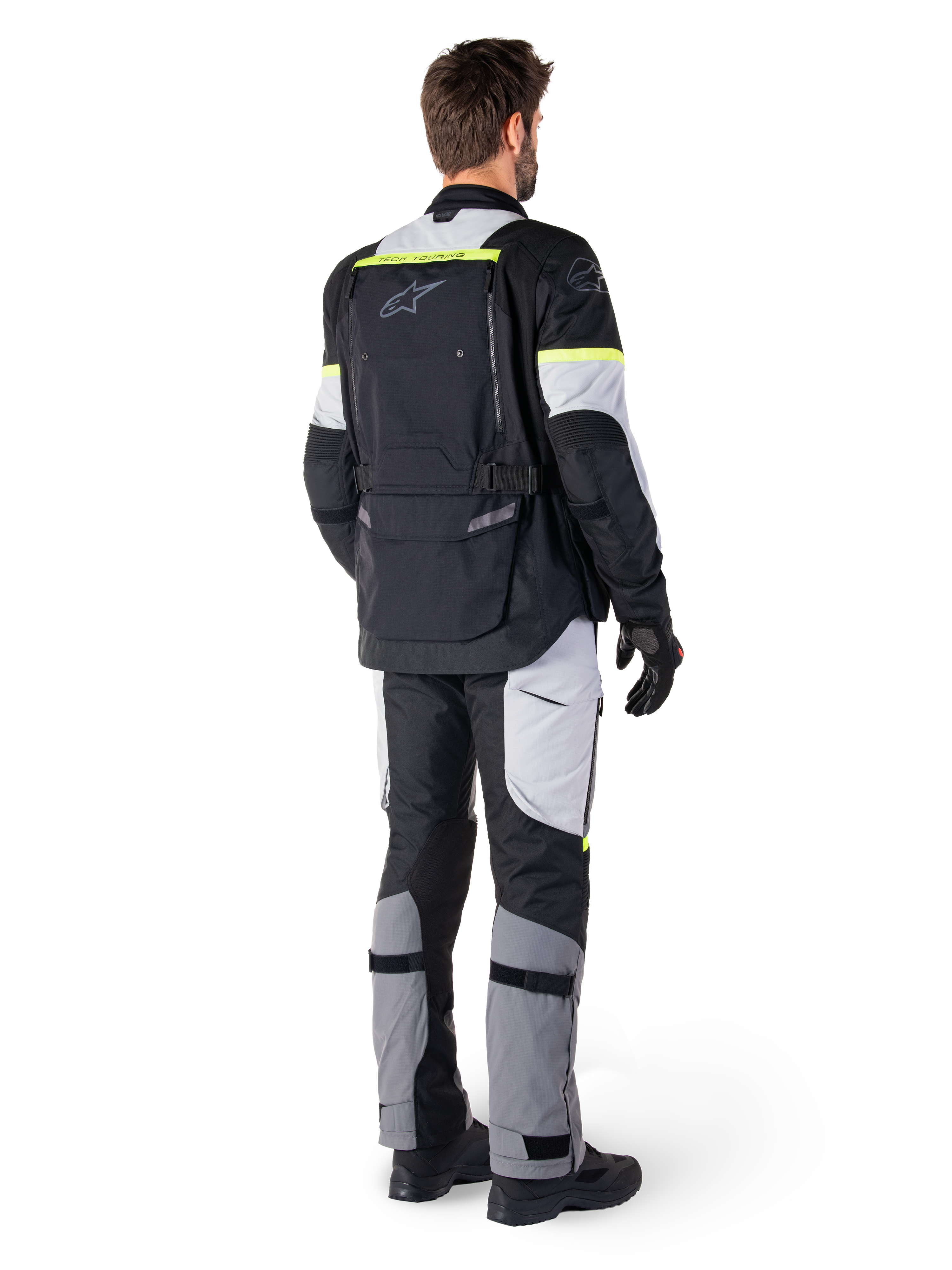 Achteraanzicht van een motorrijder die de Alpinestars Bogotá Pro Drystar® Jas in Black Ice Gray Yellow Fluo draagt, gecombineerd met bijpassende adventure touring broek, voorzien van een grote achterzak en fluorescerend gele accenten, all-season textiele motorkleding.