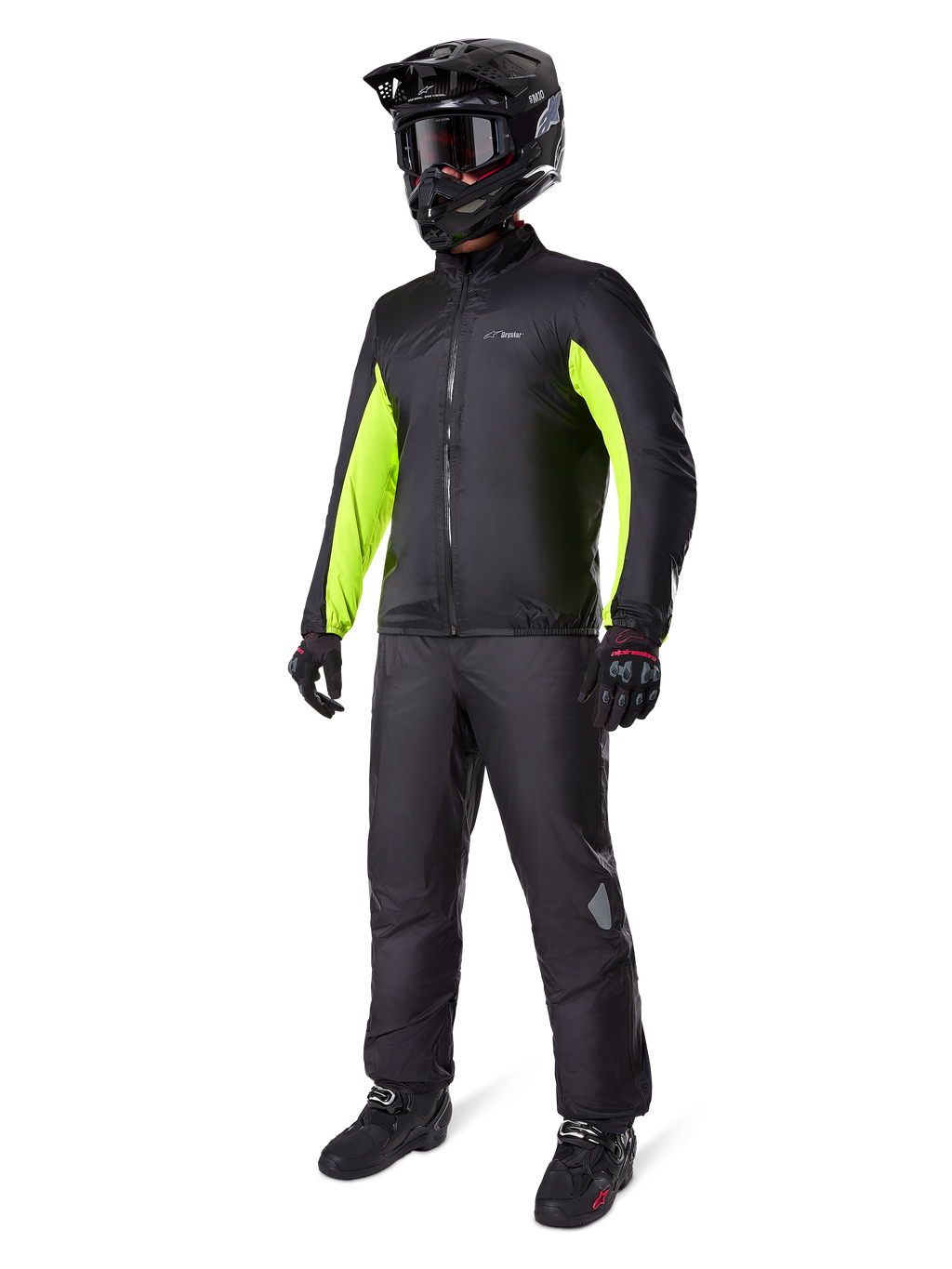 Motorrijder met Alpinestars Bogotá Pro Drystar® jas voering, zwart met felgele fluo panelen op de mouwen, gedragen met bijpassende zwarte broek, zwarte crosshelm en handschoenen, waterdichte all-season adventure uitrusting