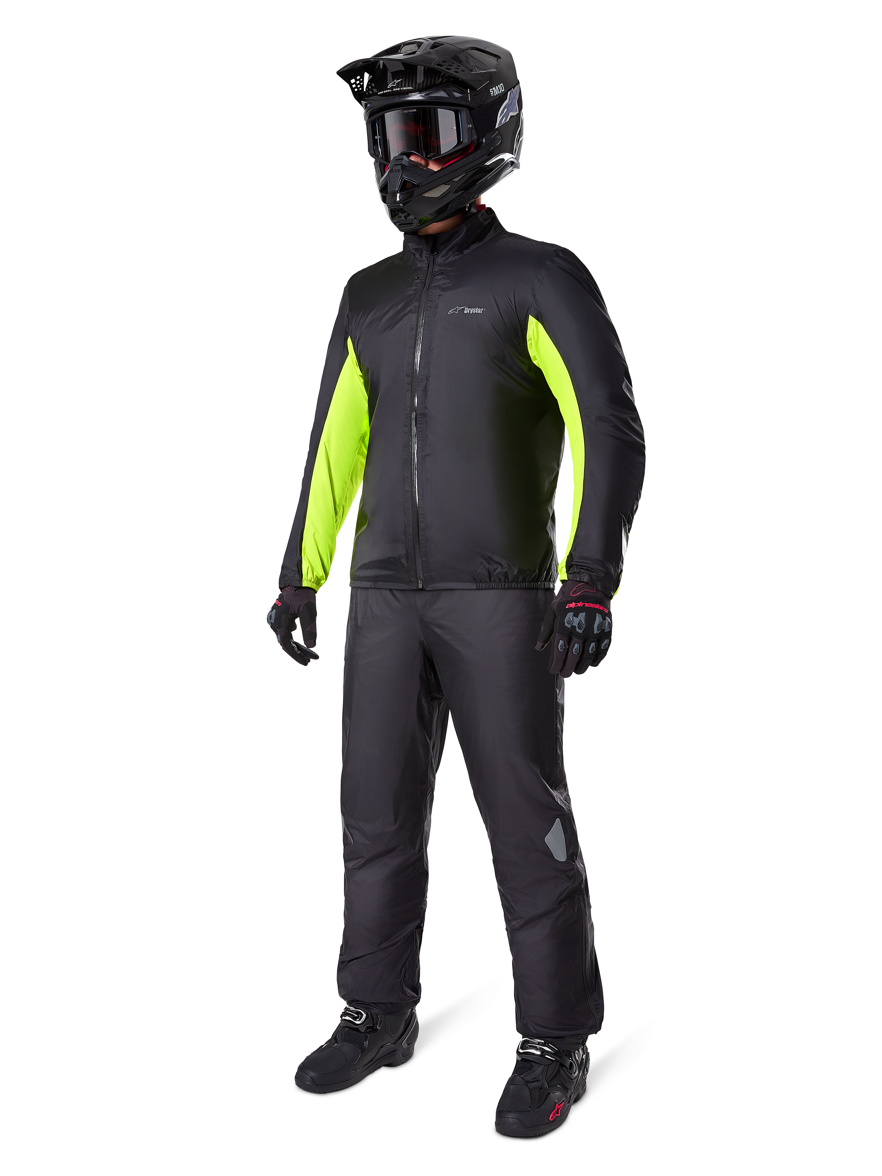 Motorrijder met Alpinestars Bogotá Pro Drystar® jas voering, zwart met felgele fluo panelen op de mouwen, gedragen met bijpassende zwarte broek, zwarte crosshelm en handschoenen, waterdichte all-season adventure uitrusting