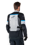 Alpinestars Bogota' Pro Drystar® Jas, adventure motorjas, ijsgrijs, zwart en cyaan, achteraanzicht met focus op het grote grijze rugpaneel met Tech Touring-branding, cyaan accenten op de mouwen en duurzame textielconstructie.