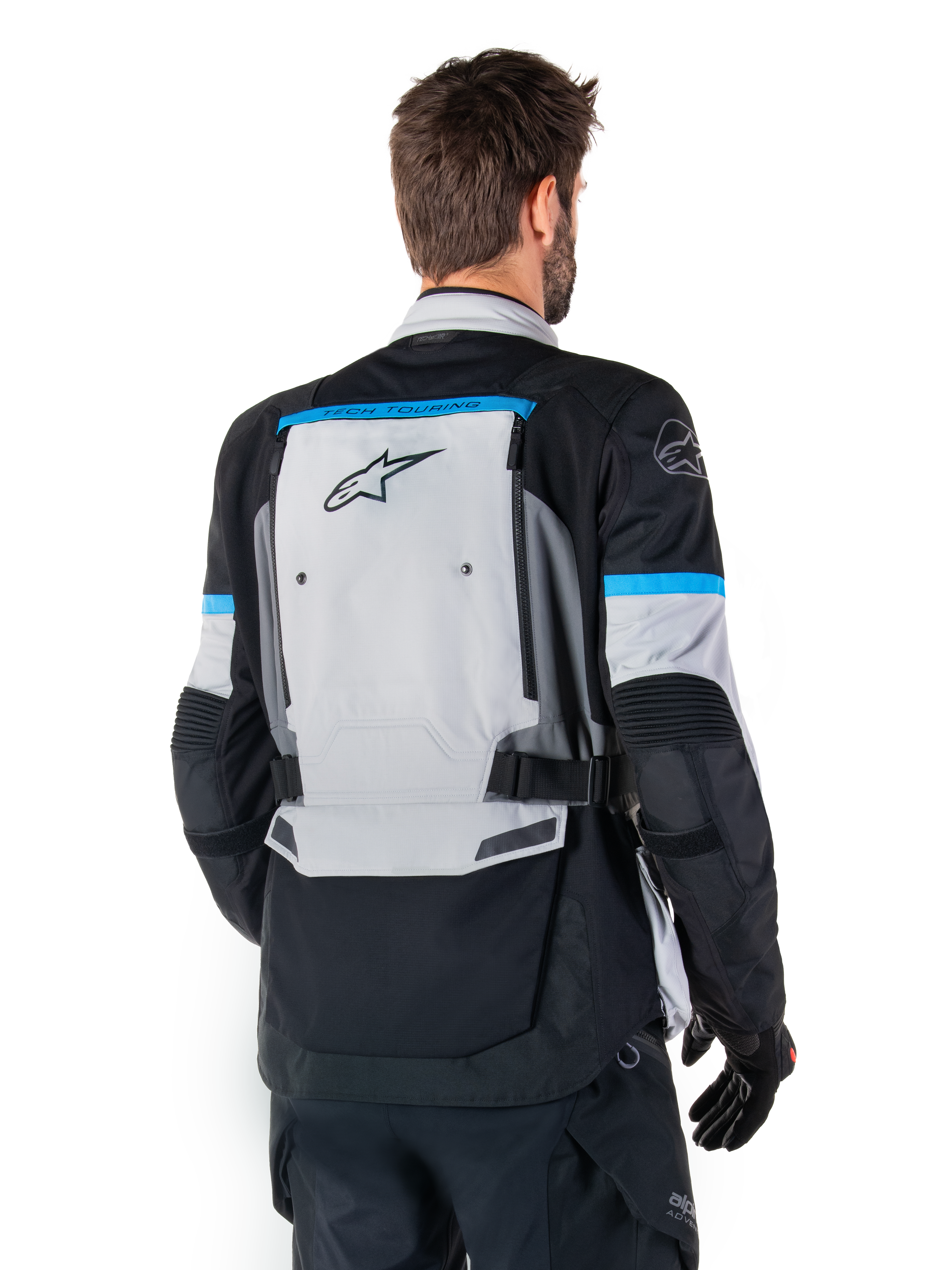 Alpinestars Bogota' Pro Drystar® Jas, adventure motorjas, ijsgrijs, zwart en cyaan, achteraanzicht met focus op het grote grijze rugpaneel met Tech Touring-branding, cyaan accenten op de mouwen en duurzame textielconstructie.