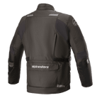 Alpinestars Andes V3 Drystar® jas, motorjas, zwart, achteraanzicht met een grote utiliteitszak onderaan met Alpinestars-logo, reflecterende accenten op de schouders en verstelbare tailleband, duurzaam textielontwerp voor adventure touring