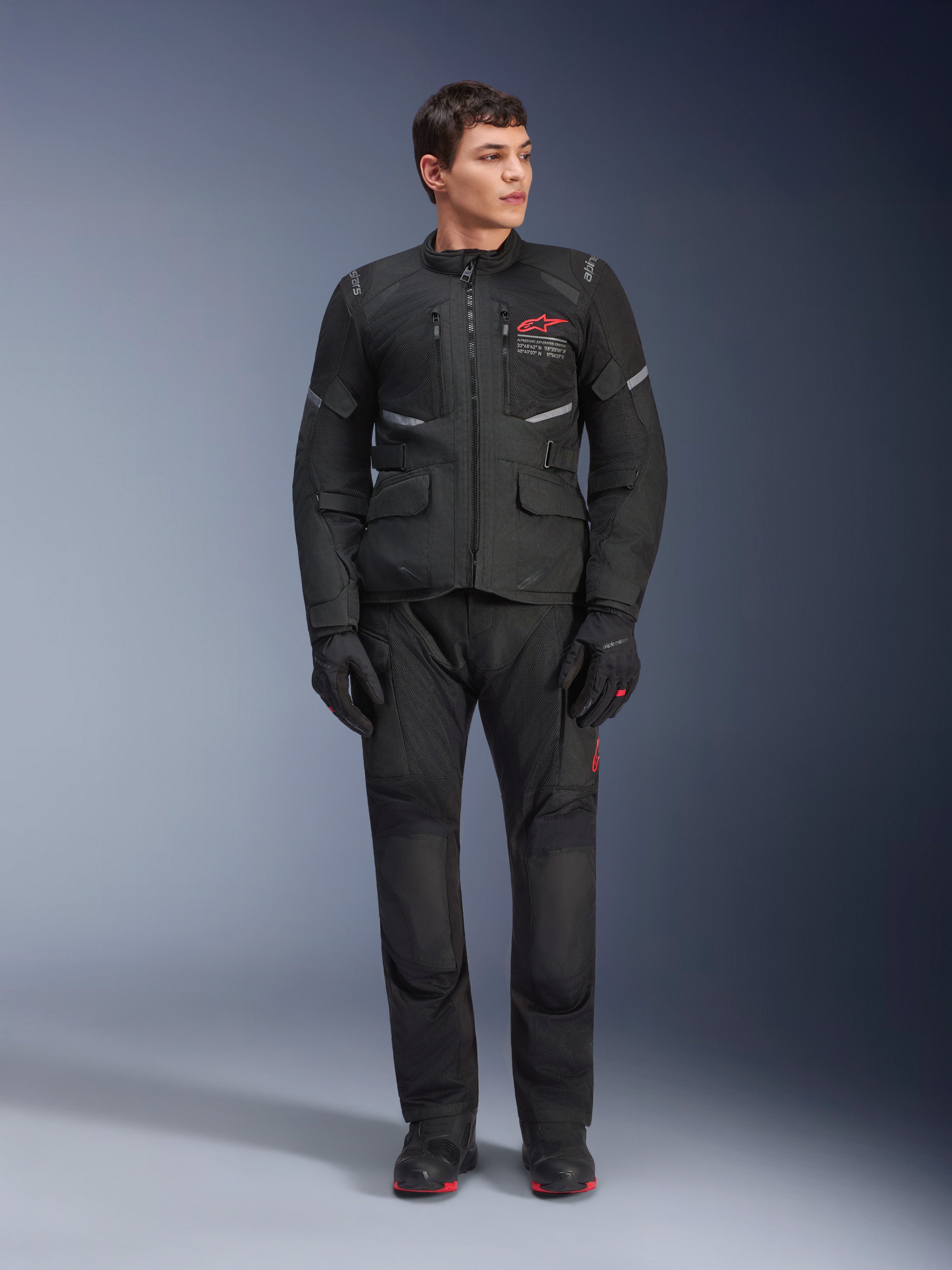 Alpinestars Andes Air Drystar® broek, motor touringbroek, zwart, voorzien van mesh ventilatiepanelen en een rood logo op de broekspijp, gedragen als onderdeel van een complete motoroutfit met bijpassende jas en handschoenen, professionele adventure touring uitrusting