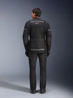 Achteraanzicht van een rijder die de Alpinestars Andes Air Drystar® Jas in het zwart draagt, voorzien van uitgebreide mesh ventilatiepanelen op de rug, een rood Alpinestars logo en reflecterende accenten, gecombineerd met een bijpassende motorbroek en handschoenen voor adventure touring.
