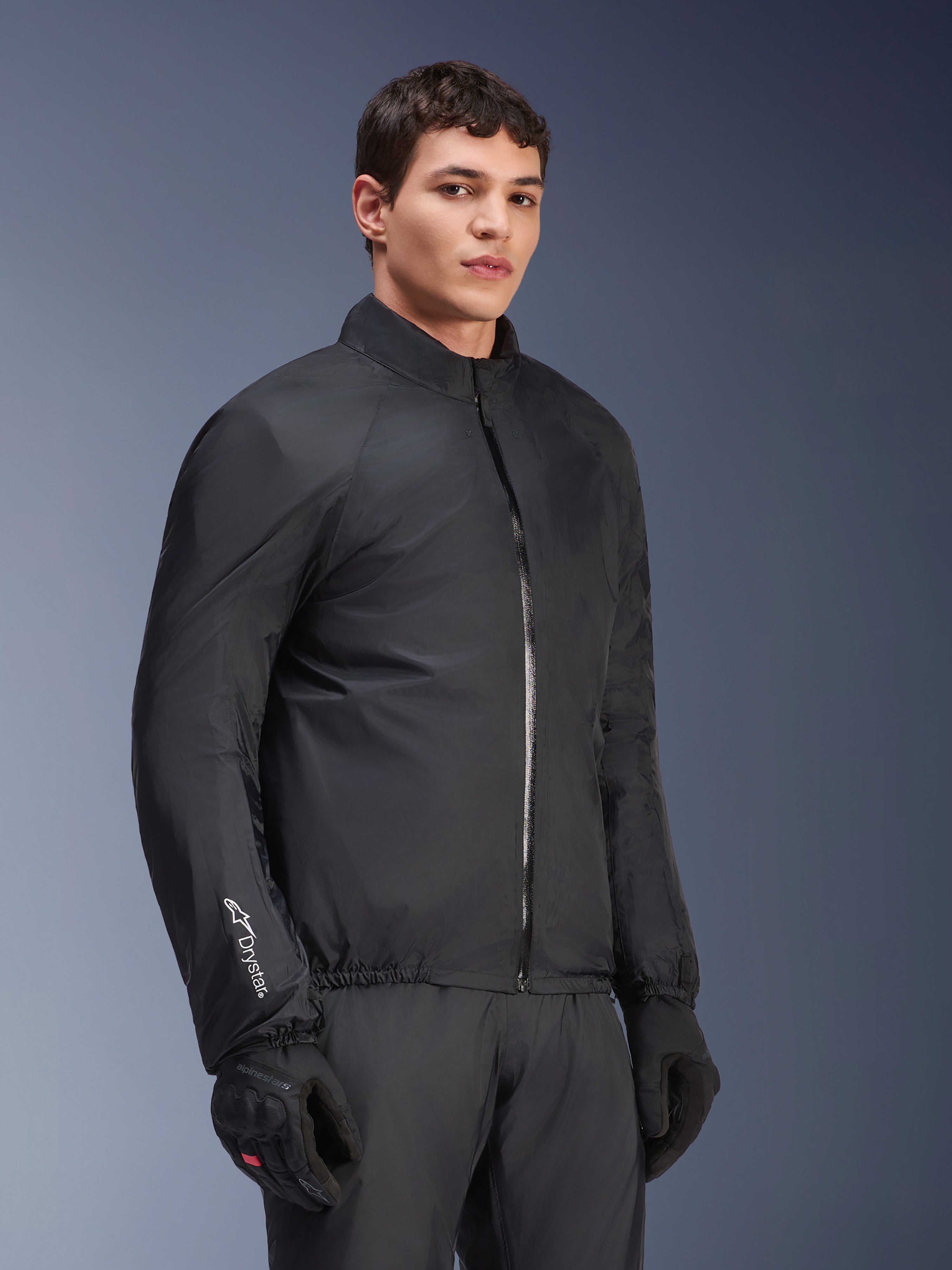 Alpinestars Andes Air Drystar® Jas waterdicht membraan, zwart, gedragen door een mannelijk model met zwarte handschoenen en broek, lichtgewicht technisch textiel met 'Drystar' logo op de mouw, studio-opname