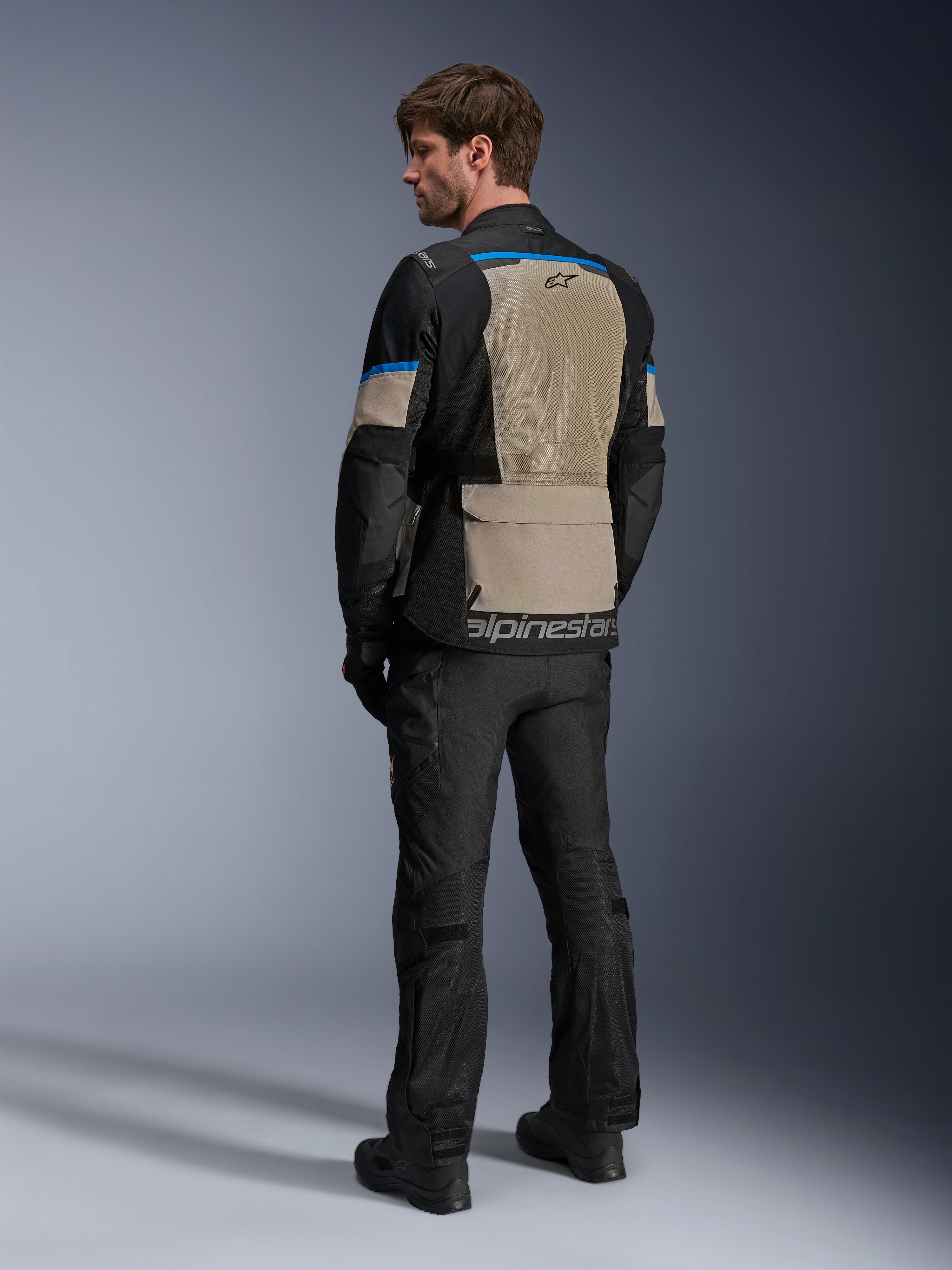 Alpinestars Andes Air Drystar® Jas, Black Laurel Gray en Bright Blue, achteraanzicht met groot mesh ventilatiepaneel op de rug, logo op de onderste zoom, gedragen met zwarte motorbroek en laarzen